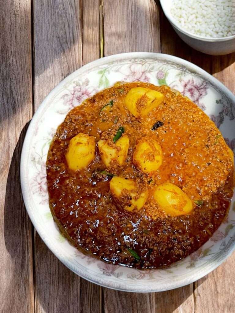 aloo keema arranged in white bowl on wooden table