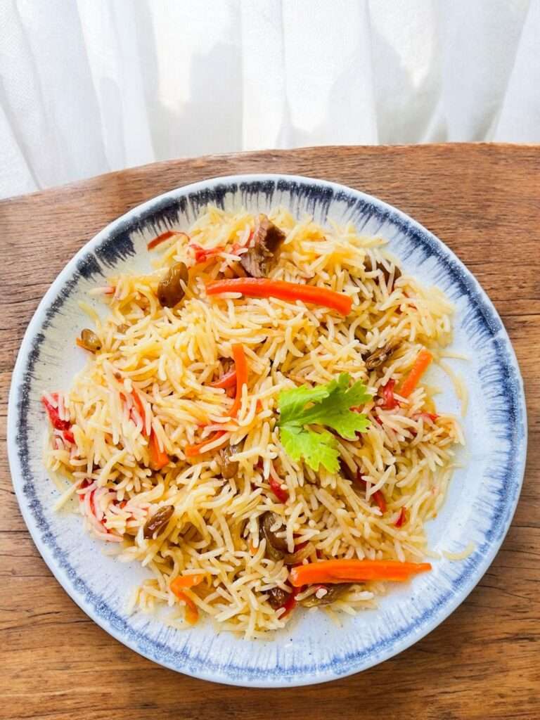 Kabuli Pulao arranged in white plate on wooden table