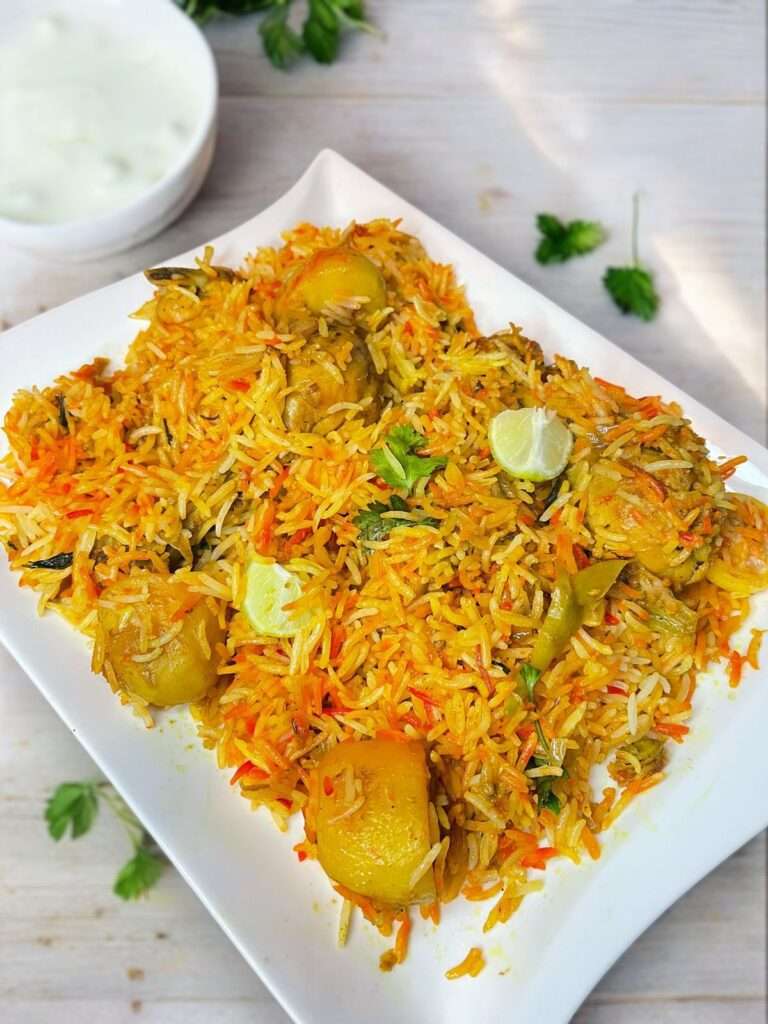 Pakistani chicken biryani arranged in a white plate placed on light wood table