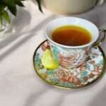 lemon ginger turmeric tea arranged in a floral cup on a neutral linen