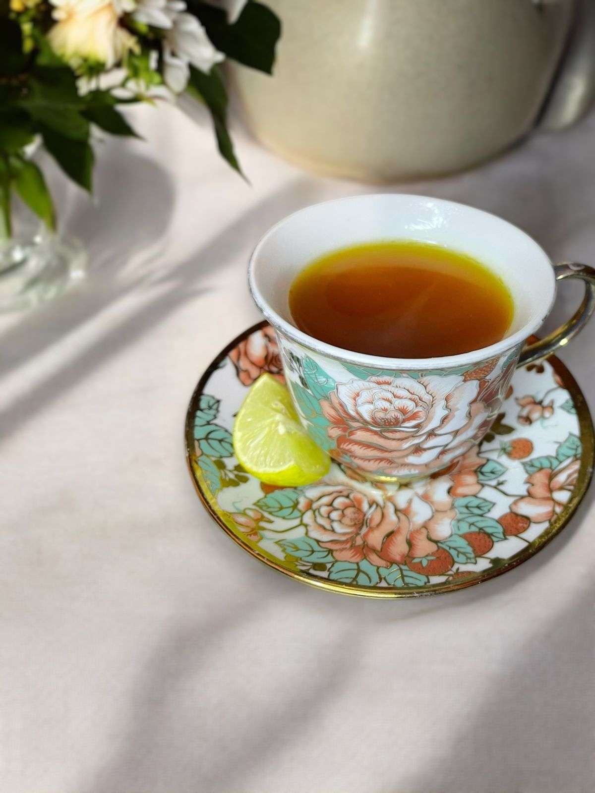 lemon ginger turmeric tea arranged in a floral cup on a neutral linen