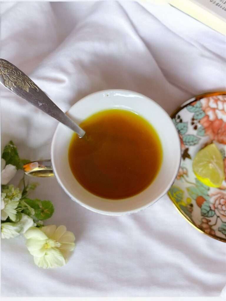 lemon ginger turmeric tea arranged in a floral cup placed on neutral linen