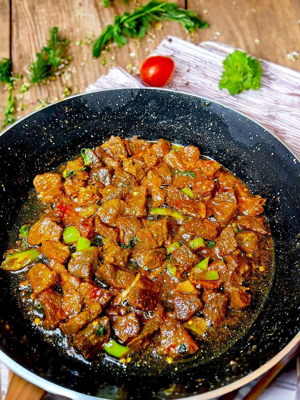 beef stir fry arranged in black pan on wooden table