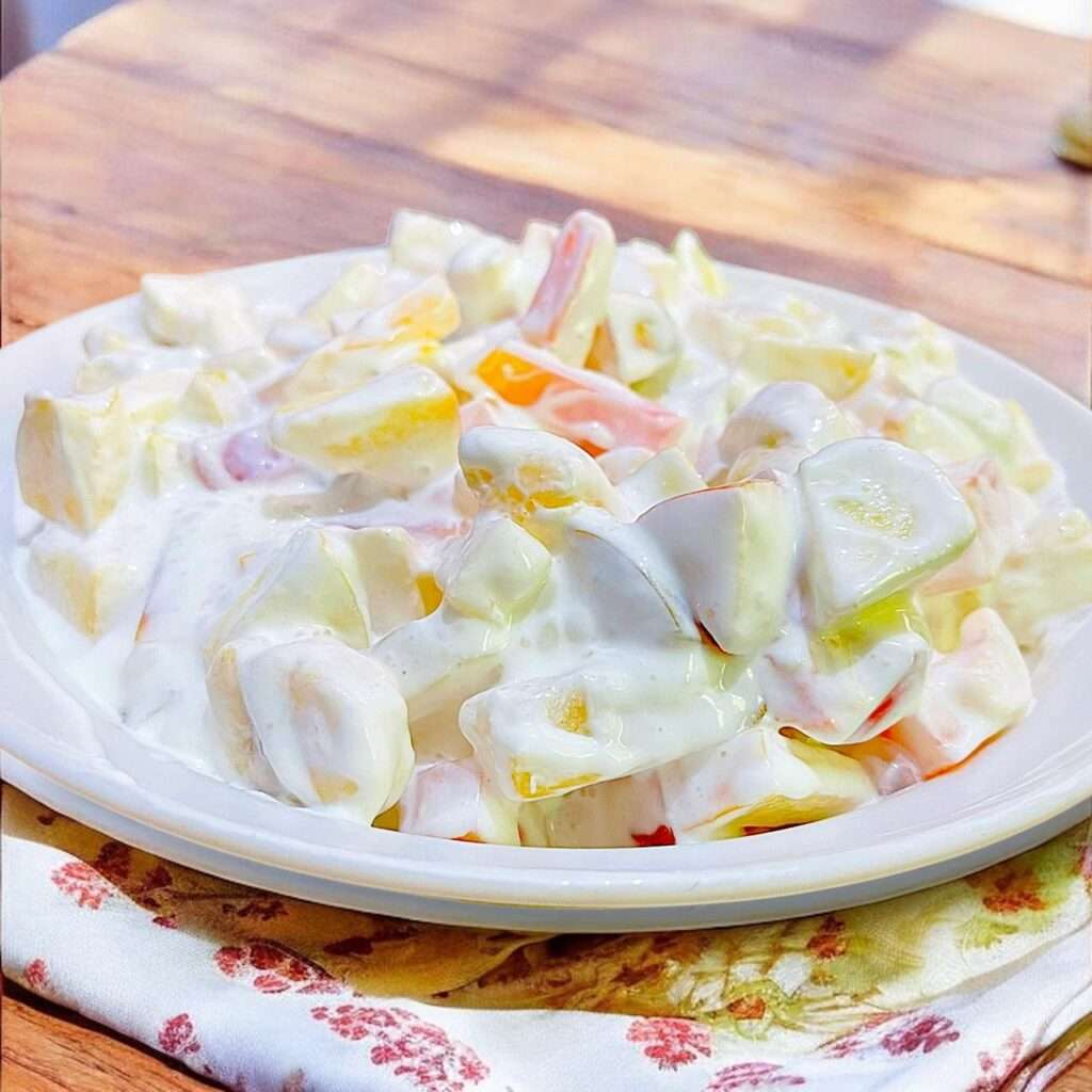 cream fruit chaat arranged in white bowl placed on light wooden table