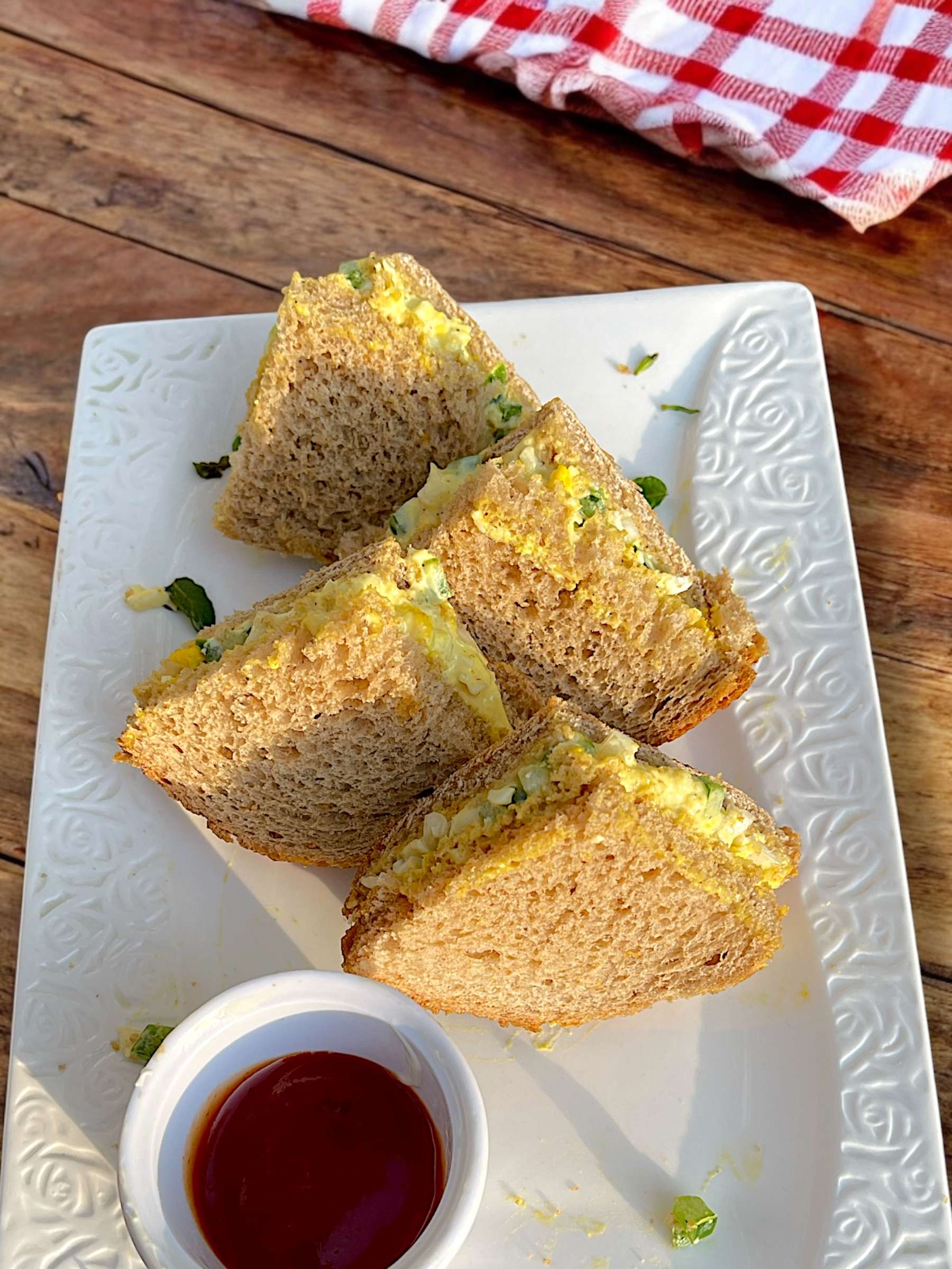 pepper and egg sandwich arranged in white dish on wooden table