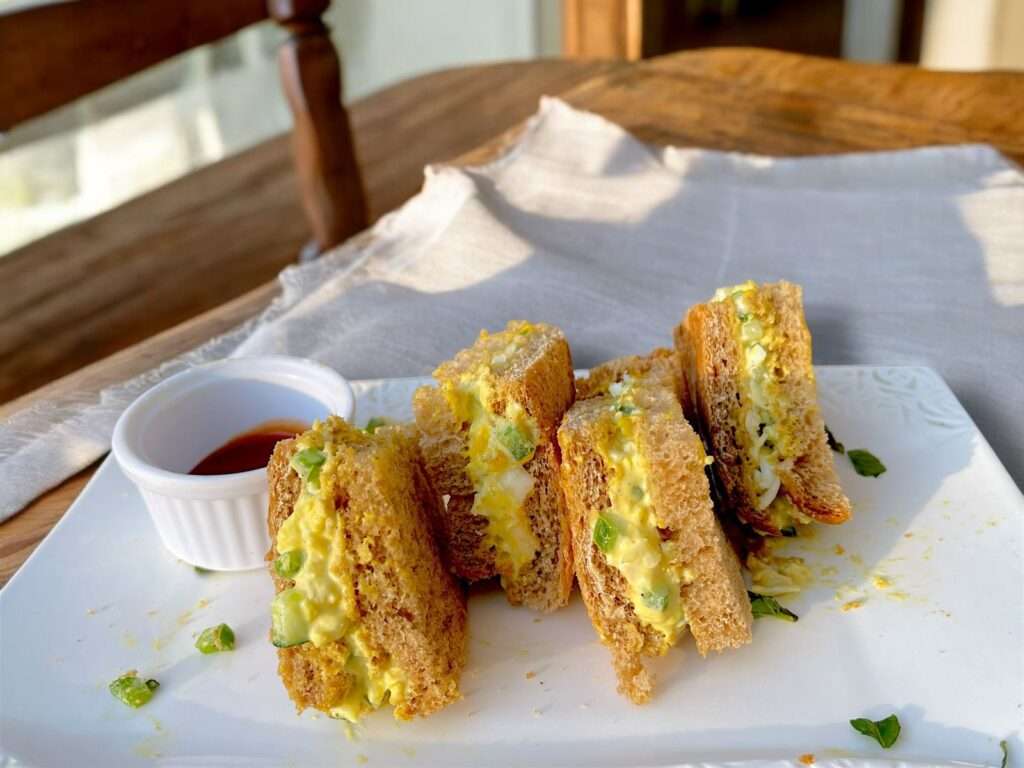 pepper and egg sandwich arranged in white dish on wooden table