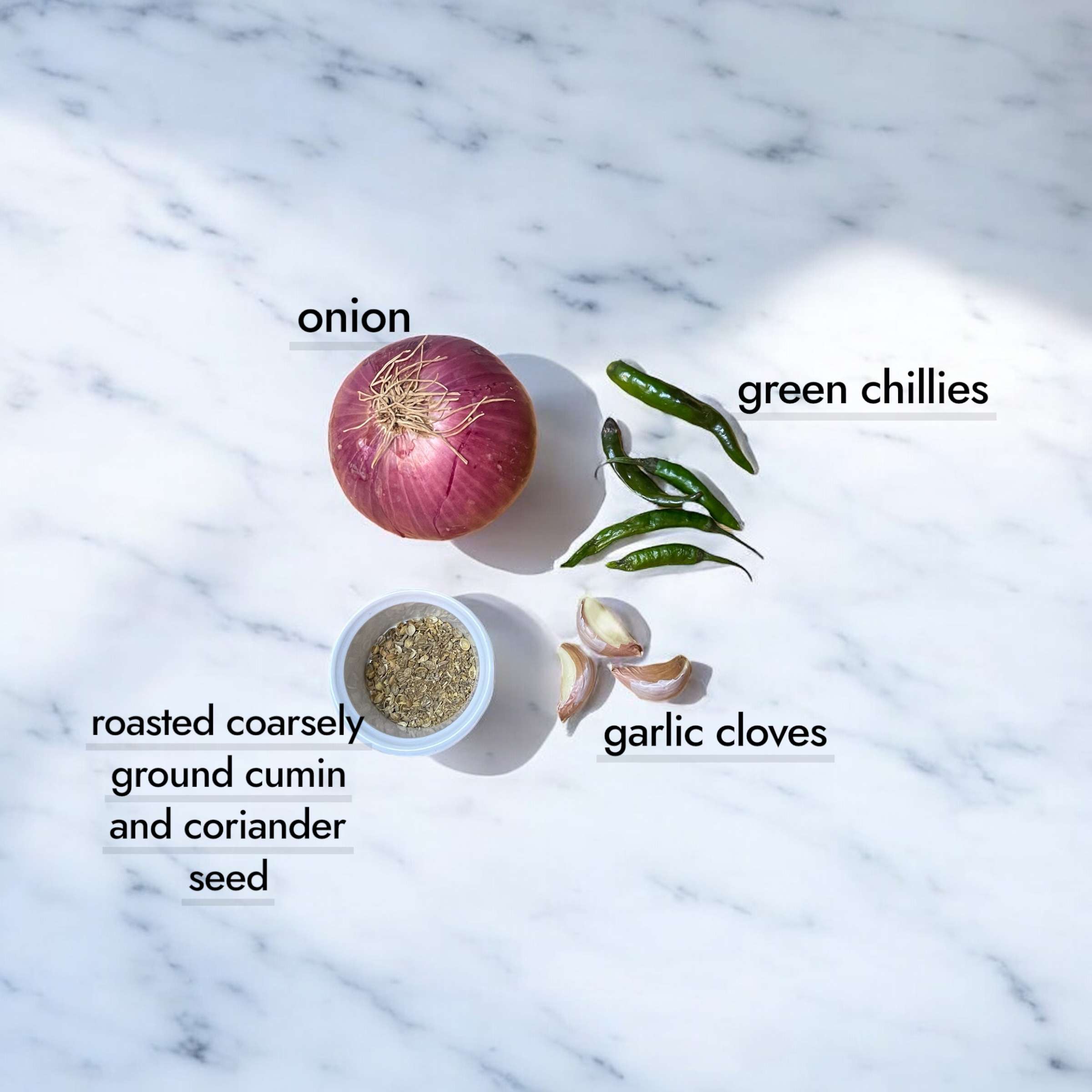 Moong masoor dal tempering ingredients arranged on marble countertop.