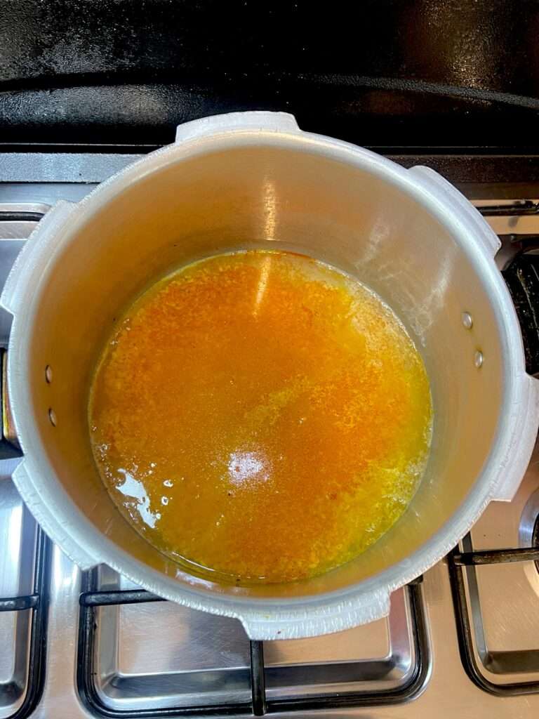 Moong masoor dal being cooked in silver pan placed on stove top.