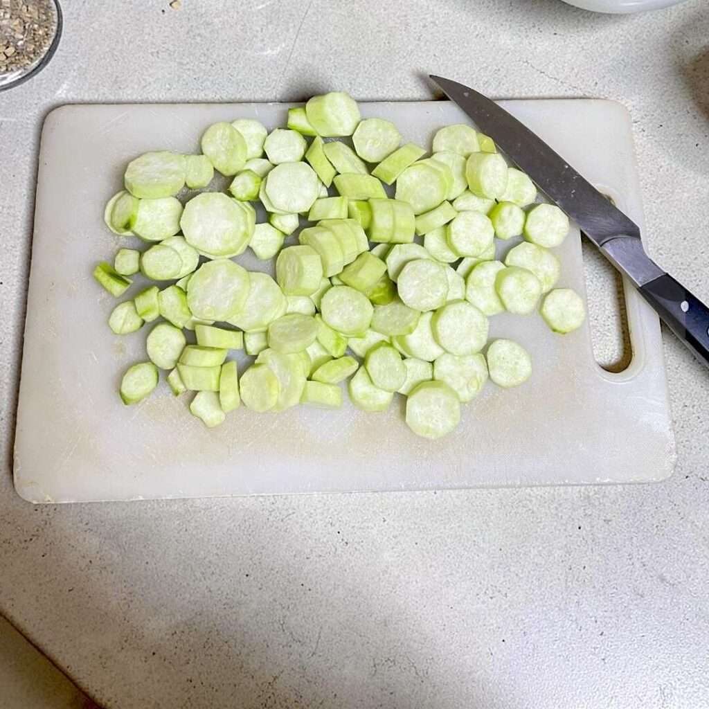 Turai sabzi cut into medium-sized round pieces, arranged on a cutting board and placed on a kitchen counter.