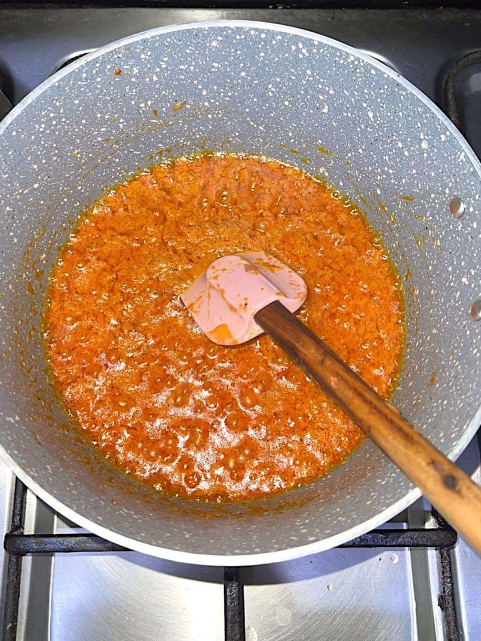 Smooth tomato and onion masala cooking in the pot.