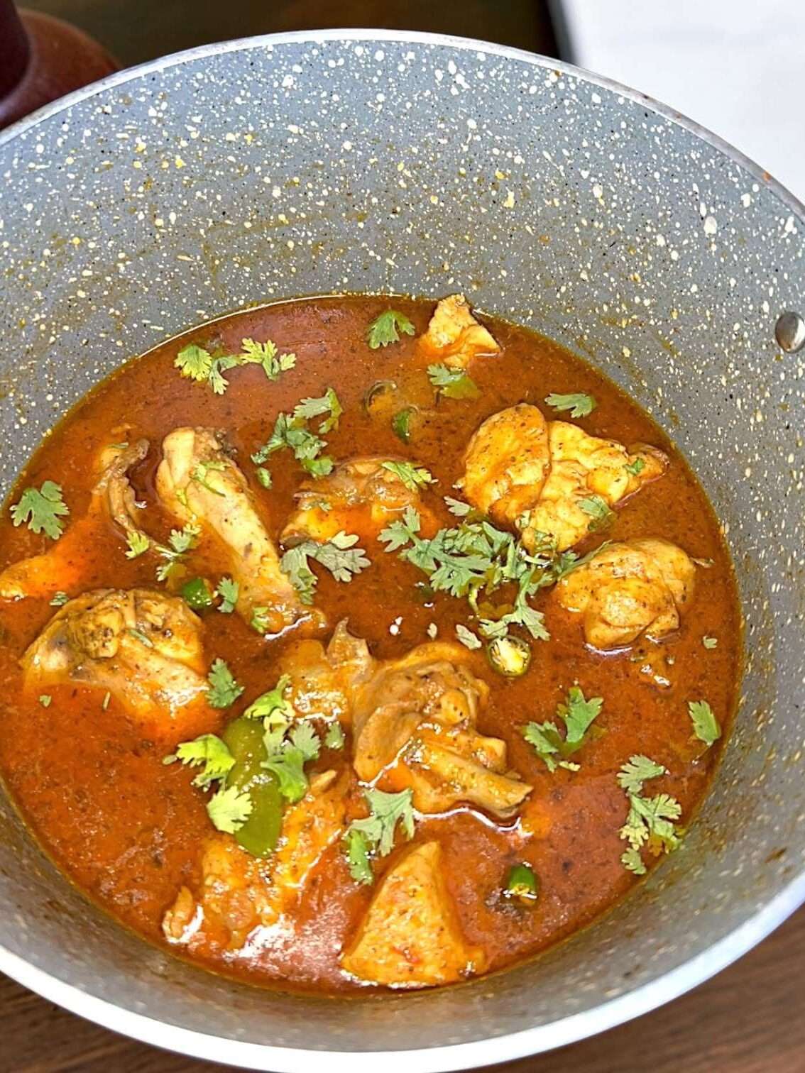 chicken curry is garnished with fresh chopped cilantro.