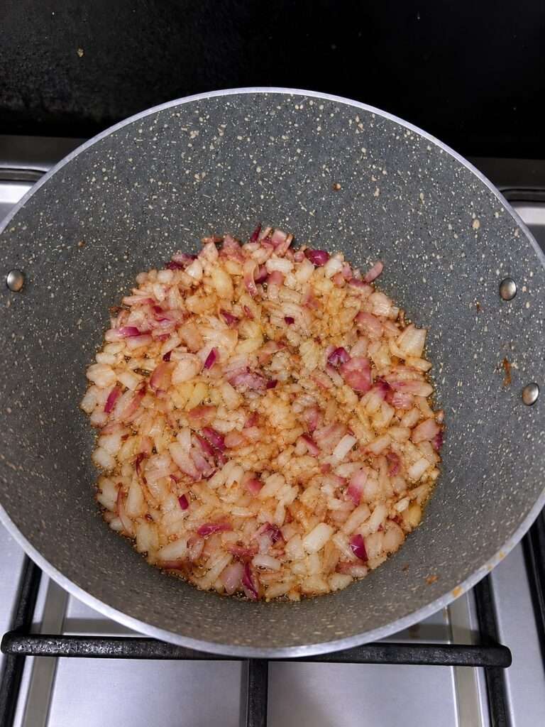 Chopped onions frying with ginger garlic paste in a pan