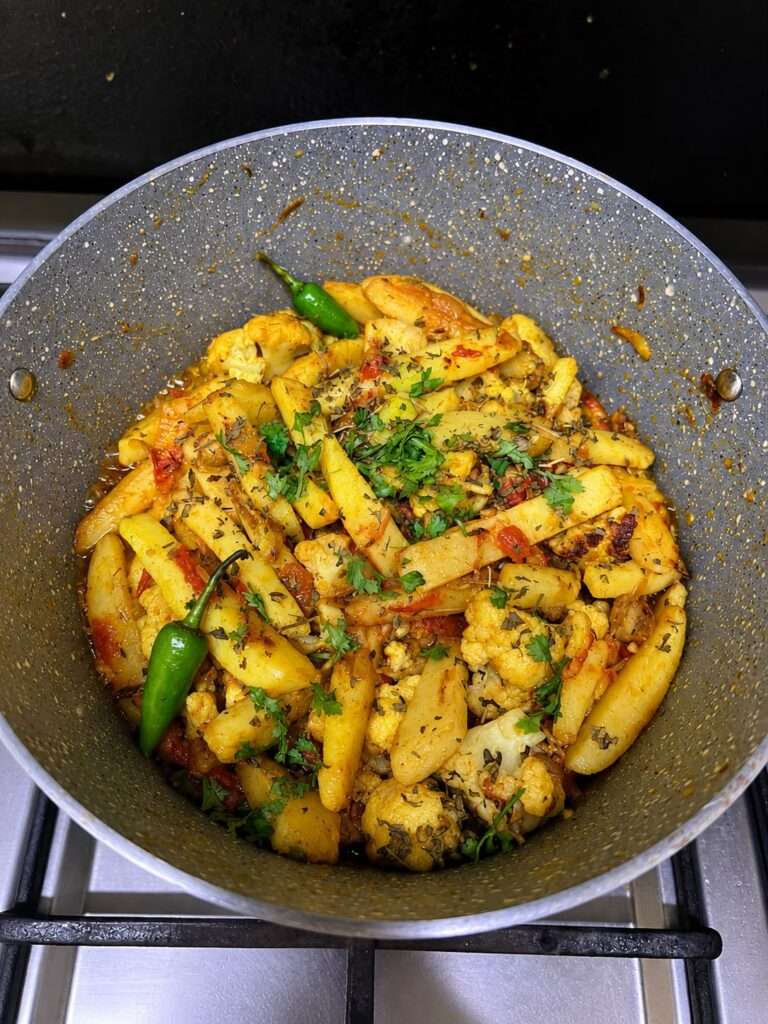 Pakistani Aloo Gobi garnished with cilantro and green chilies