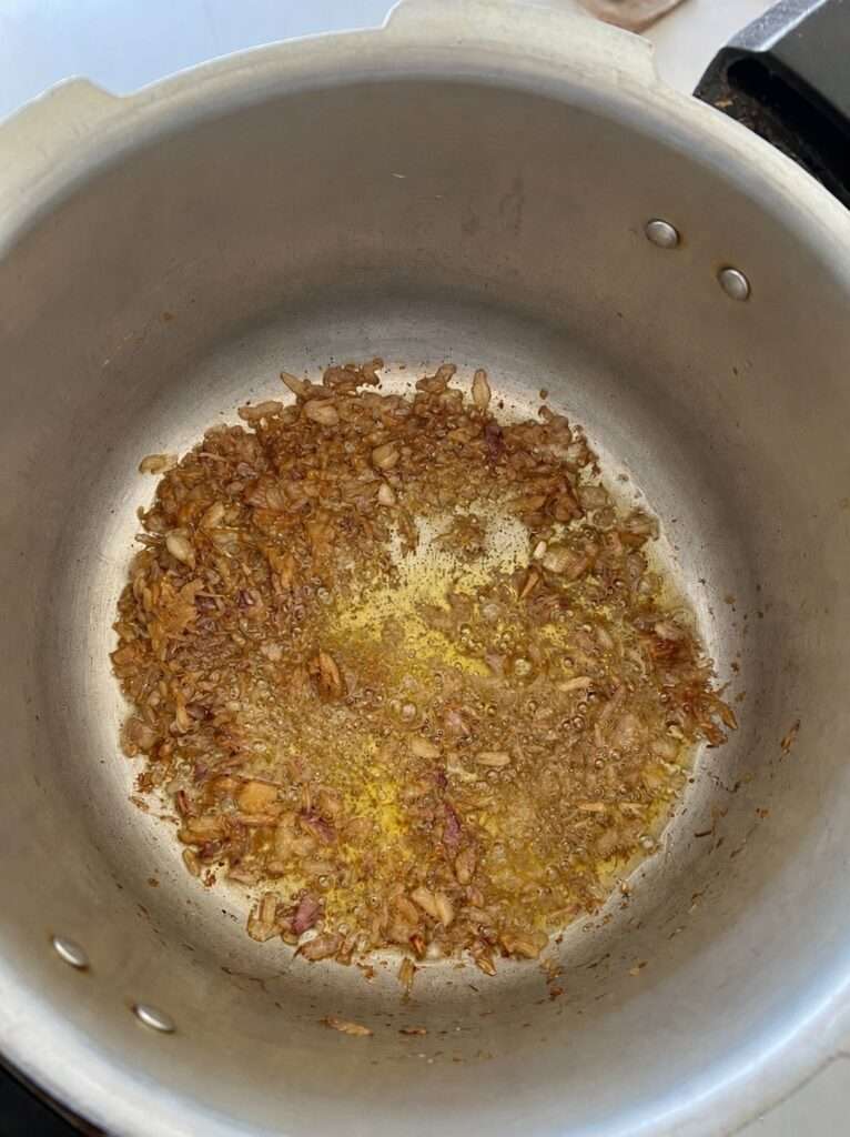 Sliced onions frying in oil in a large cooking pot