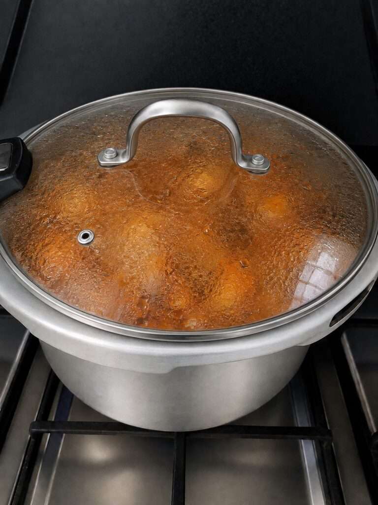 Chicken curry simmering in a covered pot on the stovetop