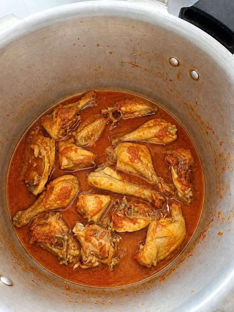 Chicken pieces simmering in rich red curry gravy