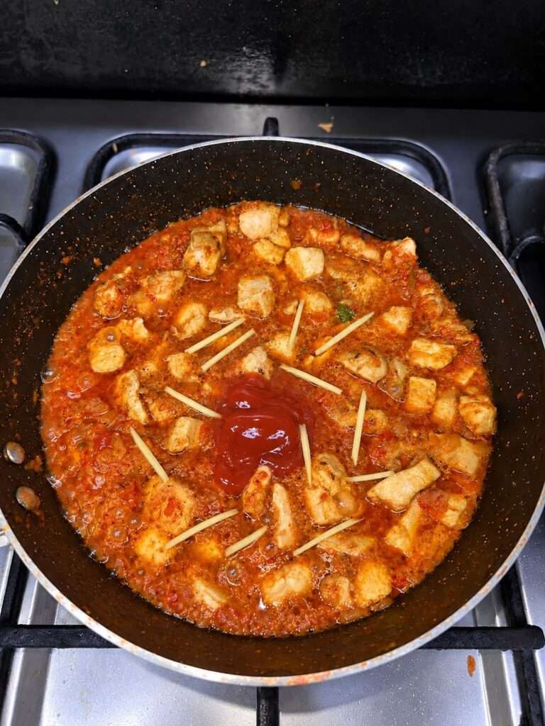 Ketchup, soy sauce and julienne-cut ginger added over chicken curry in a pan