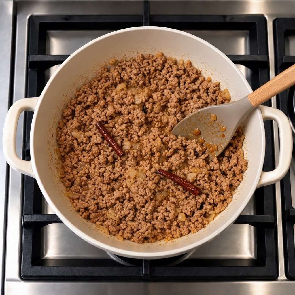 Minced meat cooking with browned onions and whole spices